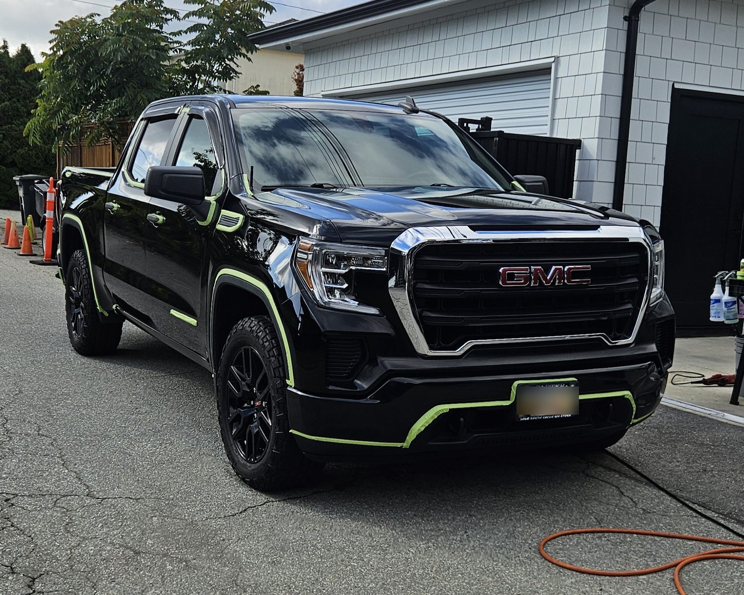 Black GMC Sierra with trim taped off, ready for paint correction by Vantique Detailing